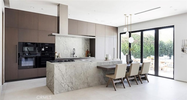 kitchen with light stone countertops, black appliances, exhaust hood, hanging light fixtures, and dark brown cabinets