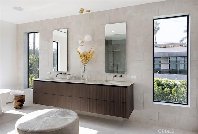 bathroom with a healthy amount of sunlight, tile walls, and vanity