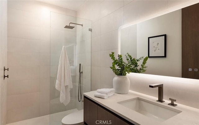 bathroom with toilet, vanity, and tiled shower