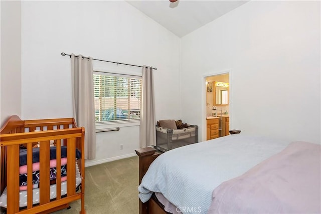 carpeted bedroom featuring high vaulted ceiling and ensuite bath