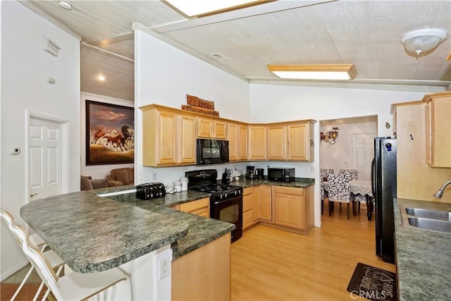 kitchen with wood ceiling, kitchen peninsula, black appliances, a breakfast bar, and sink