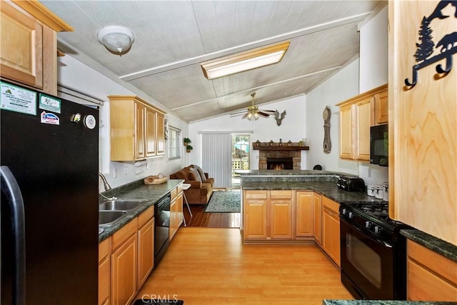 kitchen with black appliances, sink, kitchen peninsula, light wood-type flooring, and lofted ceiling with skylight