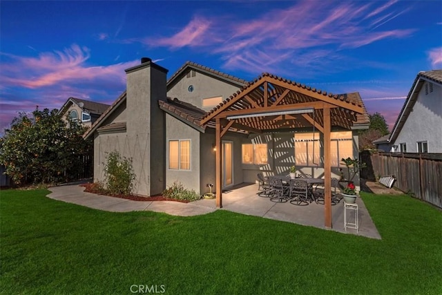 back house at dusk featuring a patio, a lawn, and a pergola