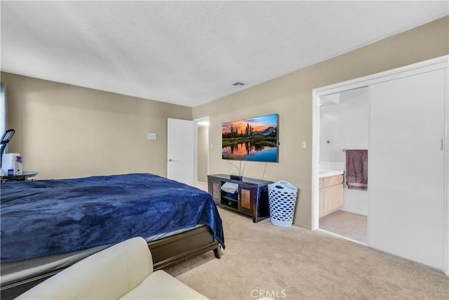 bedroom with light colored carpet, connected bathroom, and a closet