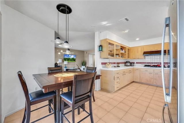 kitchen featuring light brown cabinets, hanging light fixtures, light tile patterned floors, appliances with stainless steel finishes, and tasteful backsplash