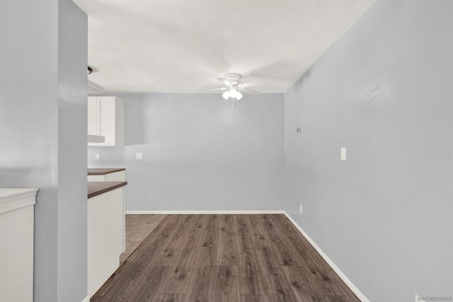 unfurnished dining area with ceiling fan and dark hardwood / wood-style floors