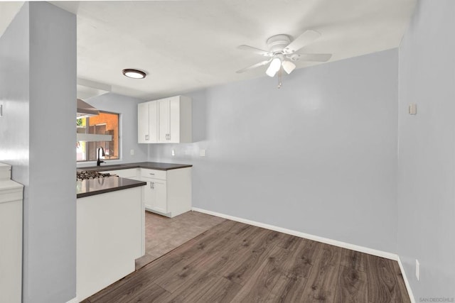 kitchen with ceiling fan, sink, wood-type flooring, and white cabinets