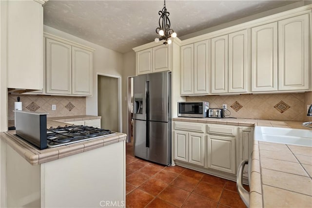 4485 Myrtle Ave, Long Beach, CA 90807 - kitchen featuring cream cabinetry, hanging light fixtures, appliances with stainless steel finishes, and tile counters