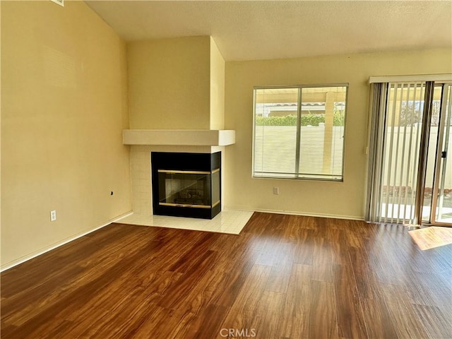 unfurnished living room featuring a multi sided fireplace and hardwood / wood-style flooring