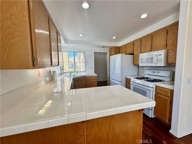 kitchen featuring tile countertops, kitchen peninsula, white appliances, dark wood-type flooring, and sink