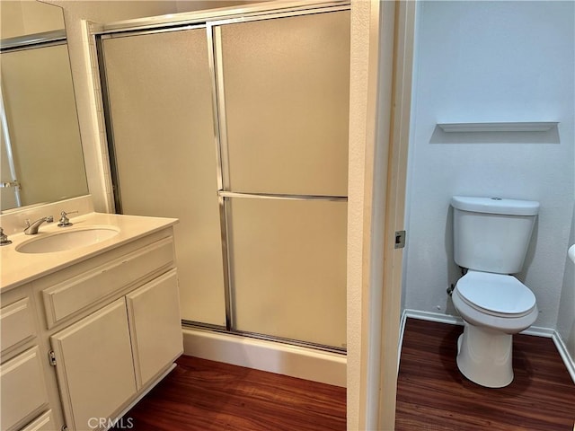 bathroom with wood-type flooring, toilet, walk in shower, and vanity