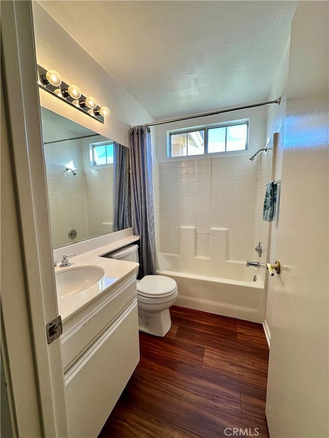 full bathroom with a textured ceiling, wood-type flooring, vanity, and shower / tub combo with curtain