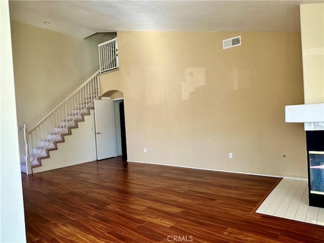 unfurnished living room featuring a multi sided fireplace, wood-type flooring, lofted ceiling, and a textured ceiling