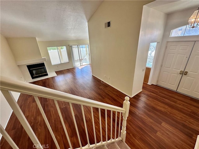 entrance foyer featuring vaulted ceiling, an inviting chandelier, dark hardwood / wood-style flooring, and a textured ceiling