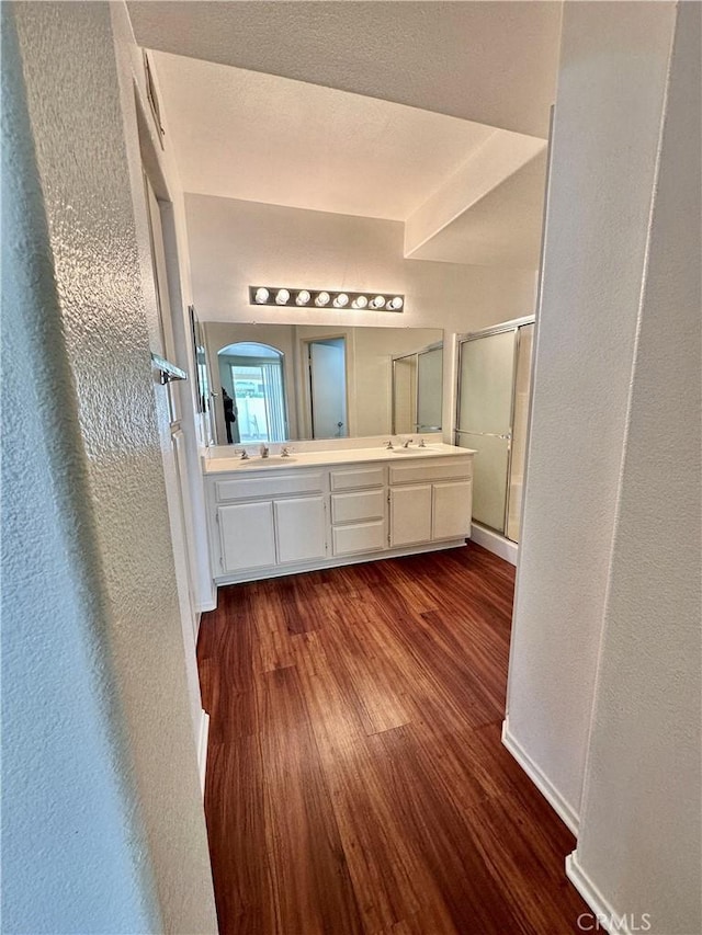 bathroom with a shower with shower door, hardwood / wood-style floors, and vanity