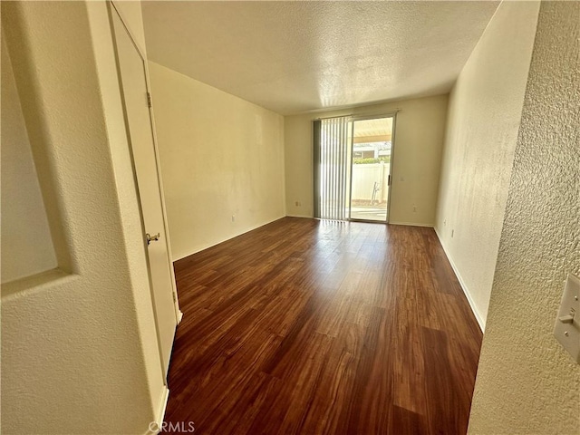 spare room featuring a textured ceiling and dark hardwood / wood-style flooring