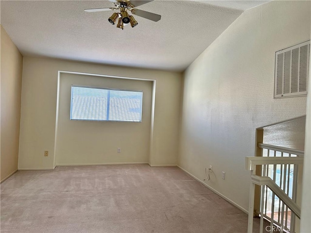 carpeted spare room with ceiling fan and a textured ceiling