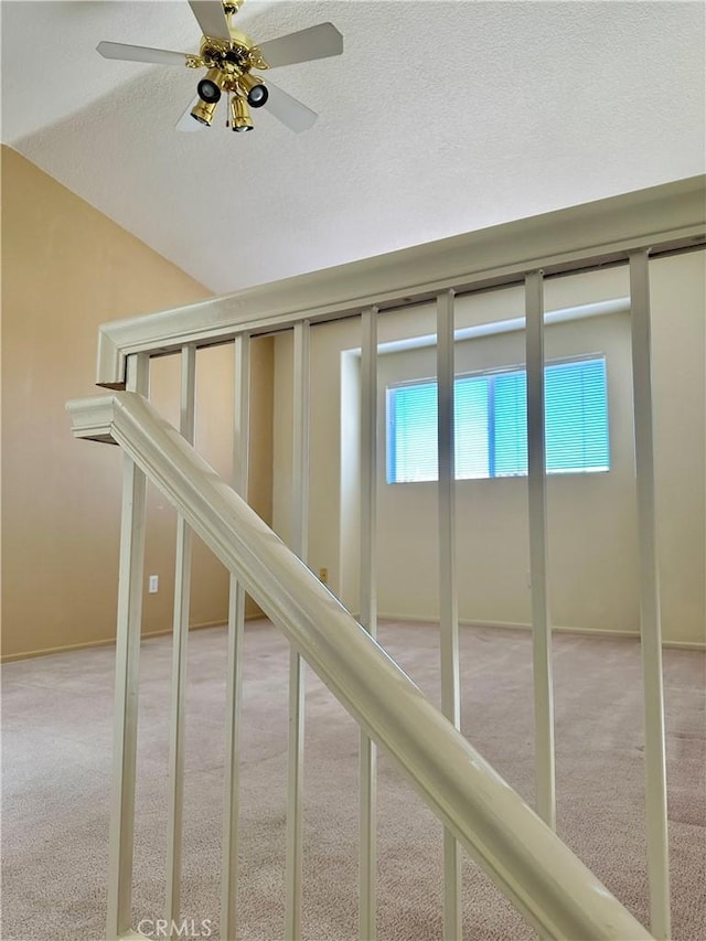 stairs with a textured ceiling, ceiling fan, a wealth of natural light, and carpet floors