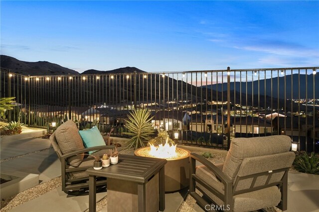 patio terrace at dusk featuring a mountain view and a fire pit