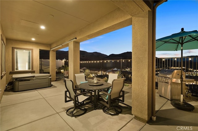 patio terrace at dusk featuring grilling area and a mountain view