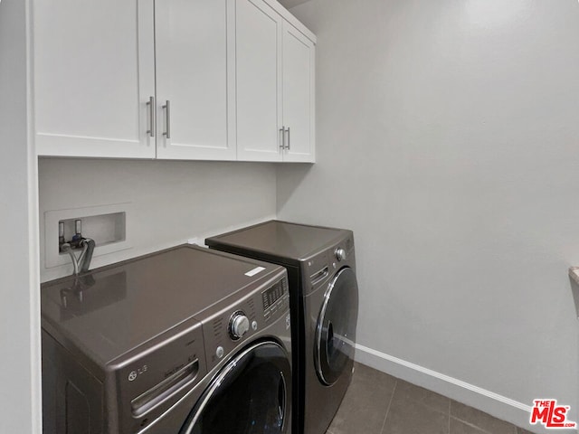 laundry area featuring washer and dryer, cabinets, and dark tile patterned floors