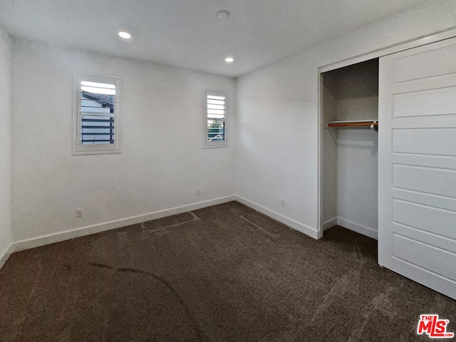 unfurnished bedroom with a closet and dark carpet