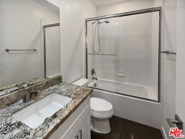 full bathroom with bath / shower combo with glass door, toilet, and vanity