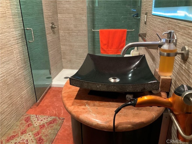 interior space featuring sink, tile walls, tile patterned floors, and a shower with door