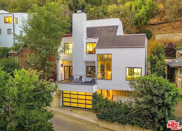 back of house with a garage and a balcony