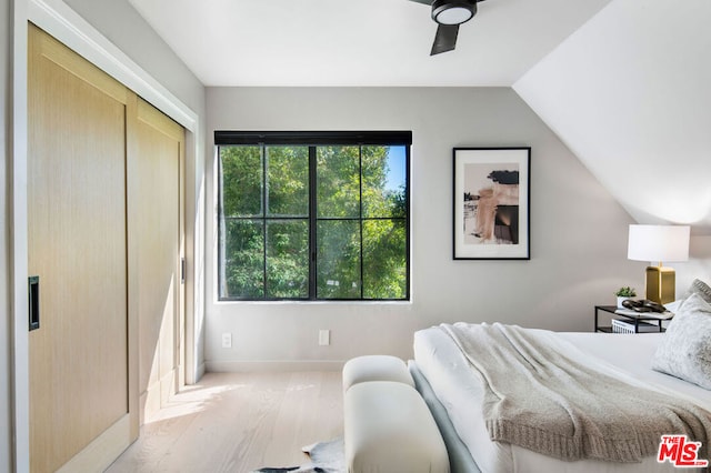 bedroom featuring ceiling fan, light hardwood / wood-style floors, multiple windows, and a closet