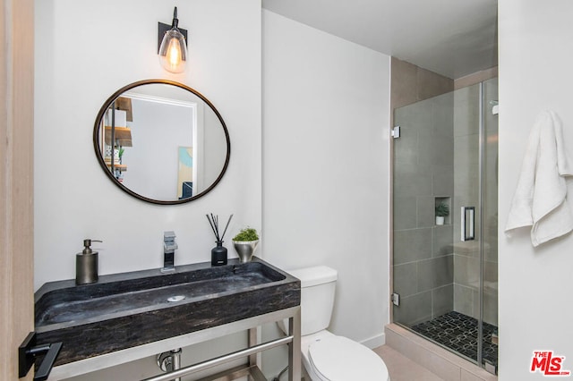 bathroom with a shower with shower door, sink, and toilet