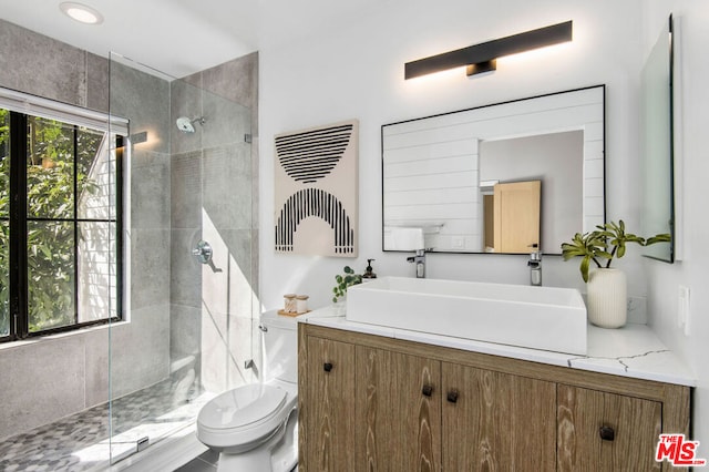 bathroom with toilet, vanity, and a tile shower