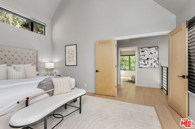 bedroom with high vaulted ceiling and light hardwood / wood-style flooring