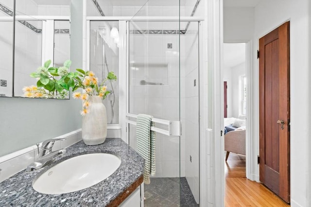 bathroom with vanity, hardwood / wood-style flooring, and a shower with door