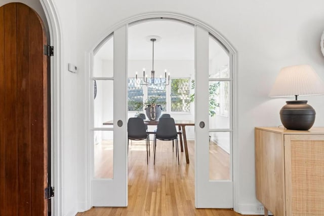 doorway featuring an inviting chandelier, light hardwood / wood-style floors, and french doors