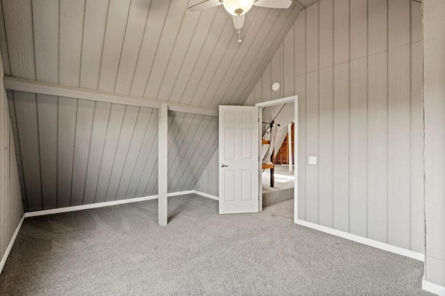 bonus room with vaulted ceiling, carpet, ceiling fan, and wood walls