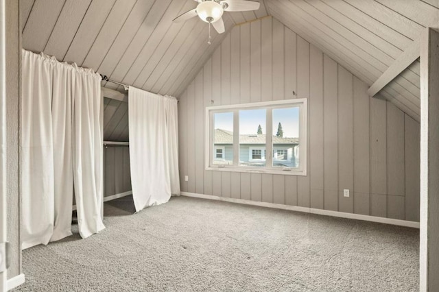 additional living space with wooden walls, ceiling fan, lofted ceiling, and carpet flooring