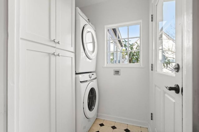 clothes washing area with cabinets and stacked washer and clothes dryer