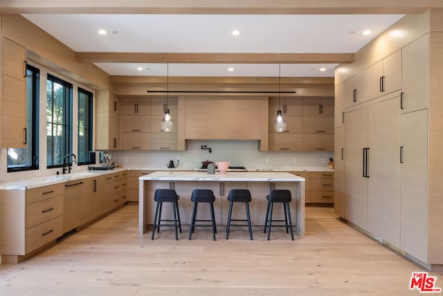 kitchen with light brown cabinets, a center island, and light wood-type flooring