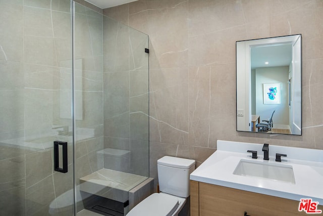 bathroom with vanity, toilet, tile walls, and a shower with door