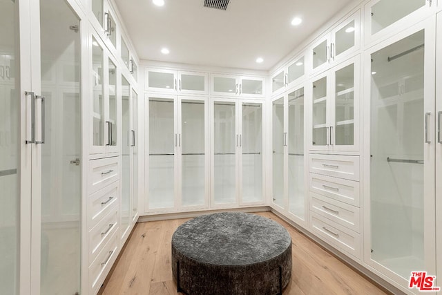 walk in closet with light hardwood / wood-style floors