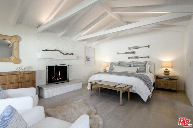 tiled bedroom with a brick fireplace and vaulted ceiling with beams