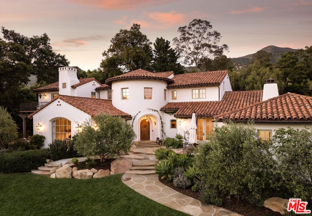 mediterranean / spanish-style house with a mountain view and a yard