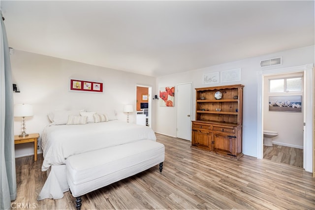 bedroom with connected bathroom and hardwood / wood-style flooring