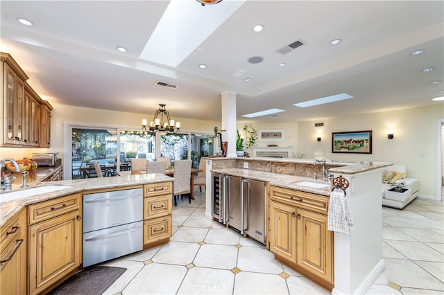 kitchen with hanging light fixtures, light stone counters, sink, and an inviting chandelier