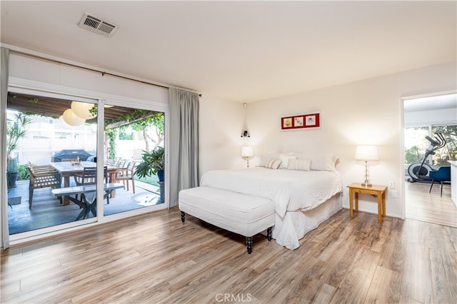 bedroom featuring access to exterior, multiple windows, and hardwood / wood-style floors