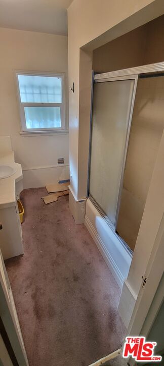 bathroom featuring bath / shower combo with glass door and vanity