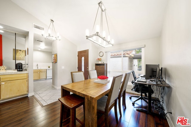 dining area with sink, lofted ceiling, wood-type flooring, and a notable chandelier