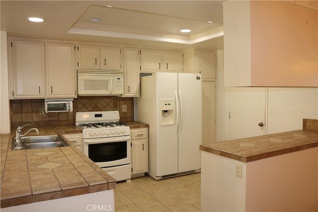 kitchen featuring white appliances, backsplash, a raised ceiling, sink, and kitchen peninsula