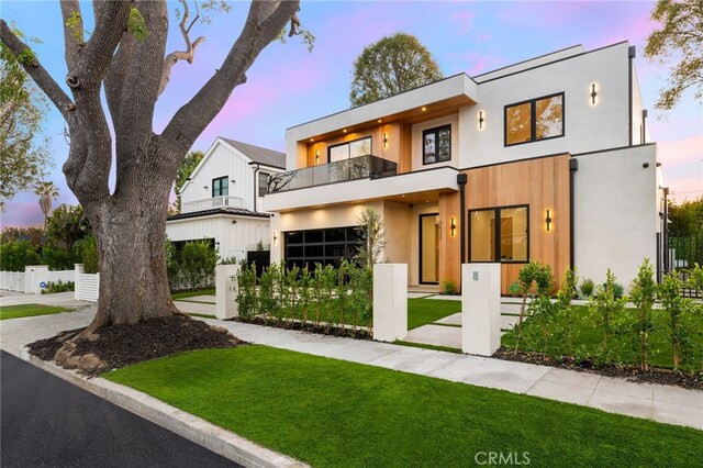 contemporary home with a balcony, a yard, and a garage